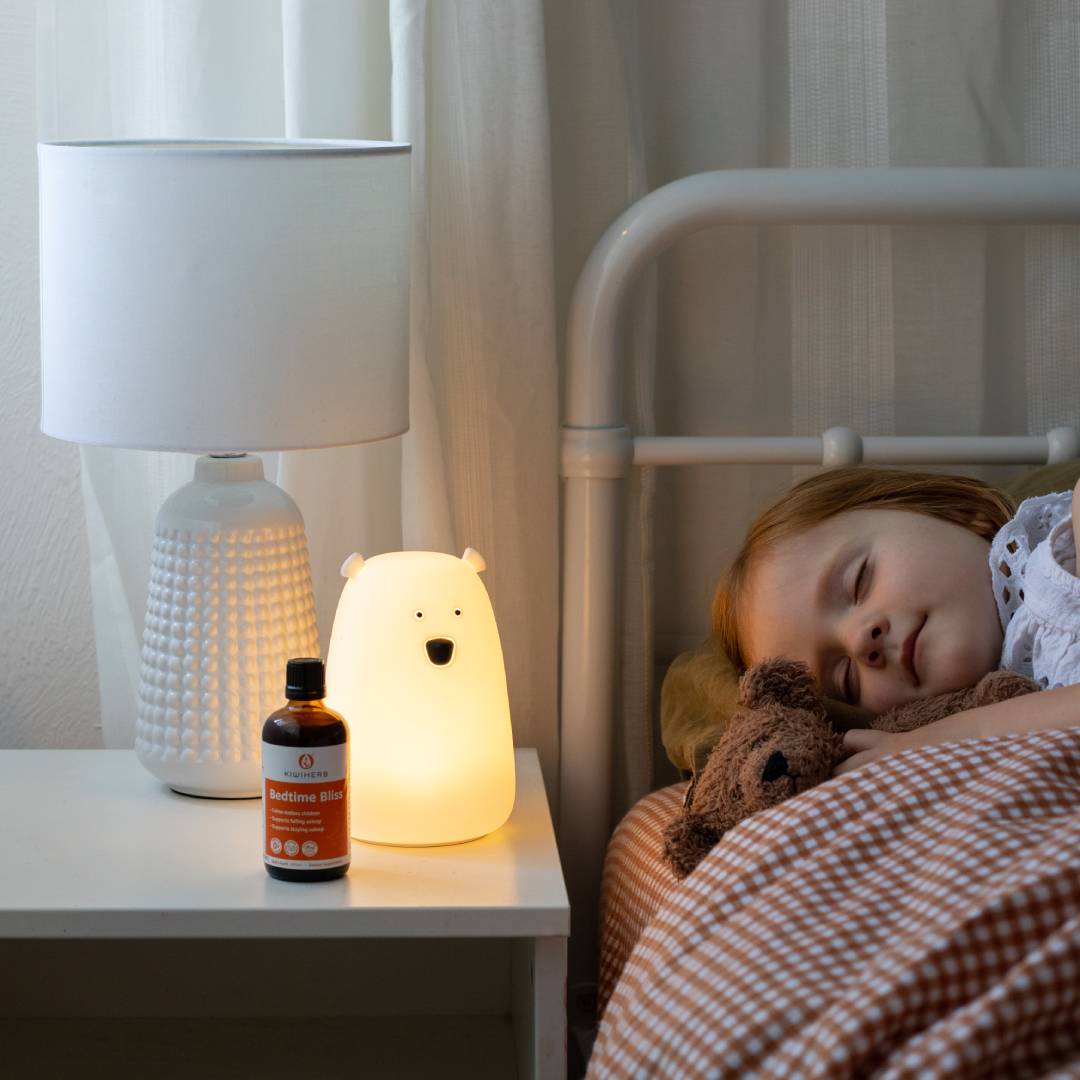 A child sleeping soundly next to a glass bottle of Bedtime Bliss