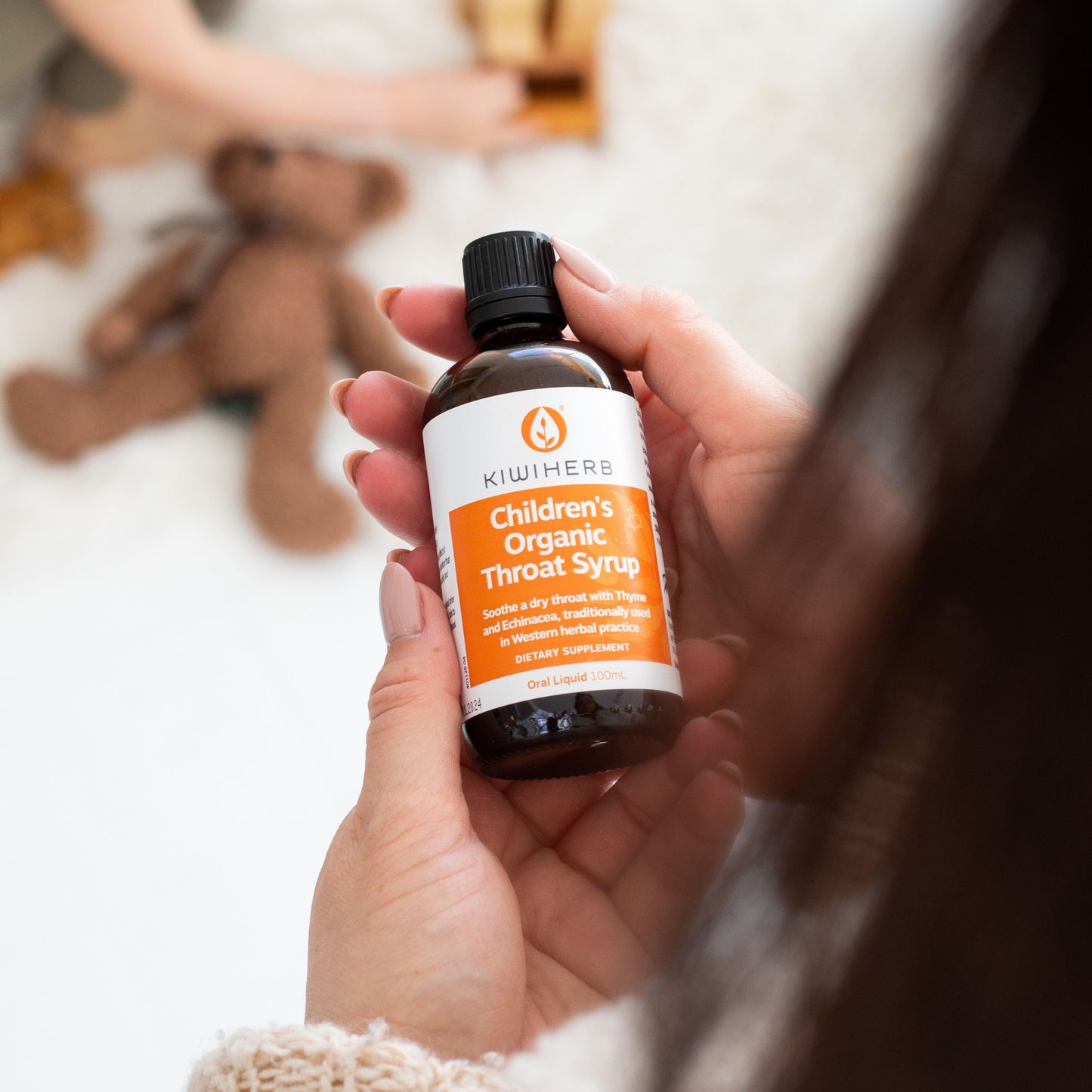 A woman holding Children's Organic Throat Syrup in her hands.