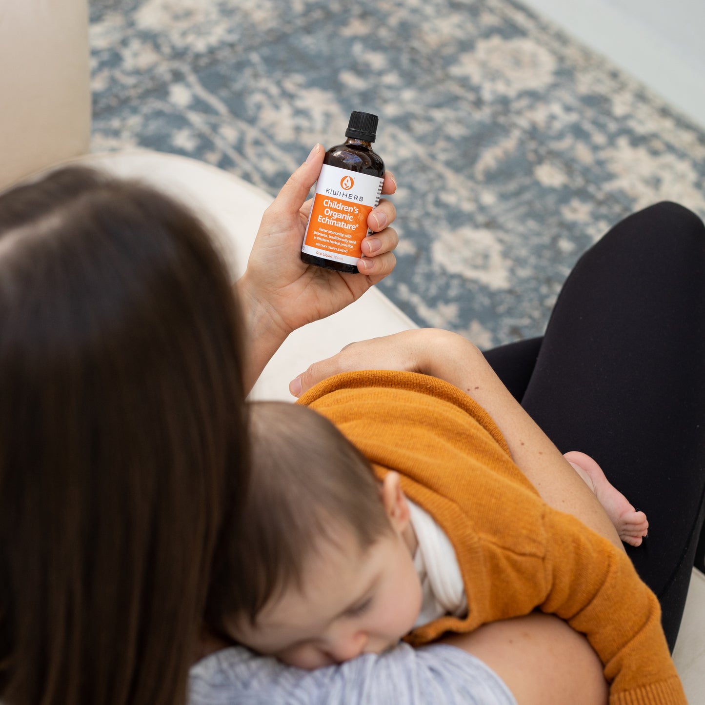 A mom holding a bottle of Children's Organic Echinature® to support and boost immunity. With herbal support of Echinacea.