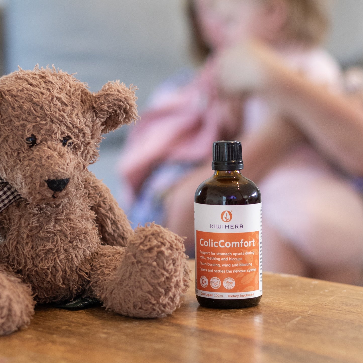 A bottle of Kiwiherb ColicComfort near a brown teddy bear.