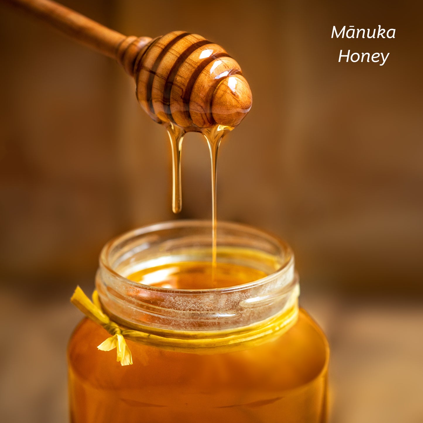 A bottle of Mānuka Honey with a honey dipper.