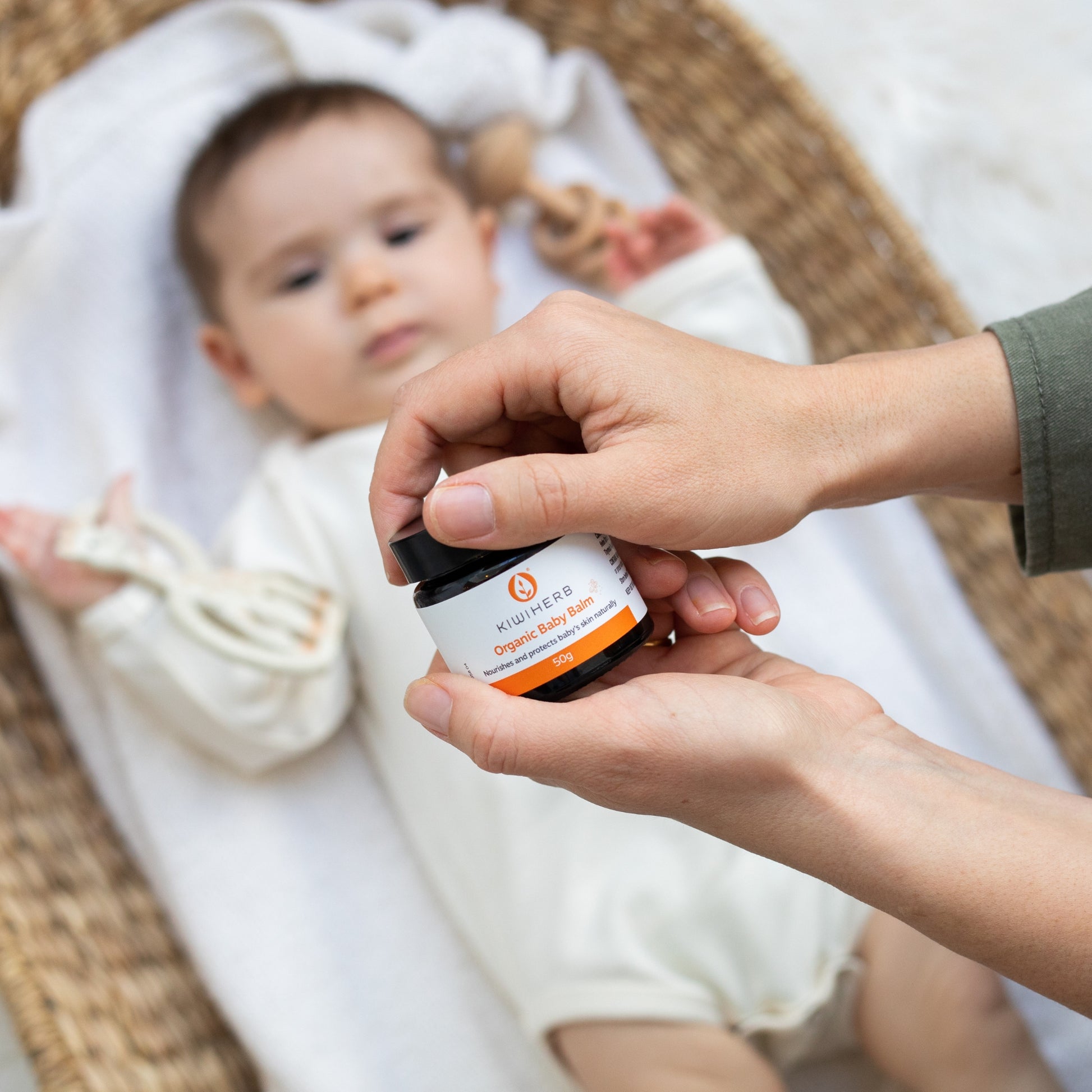 A mother opening a jar of Organic Baby Balm for her baby.