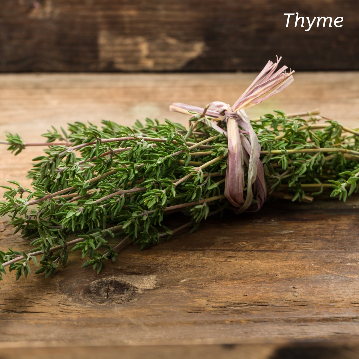 Sprigs of Thyme tied together and placed on a wooden kitchen table.
