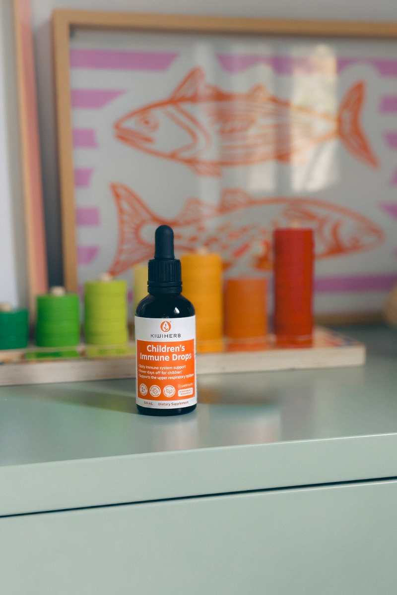 Bottle of Children's Vitamin Drops on a surface with a colorful fish painting in the background.