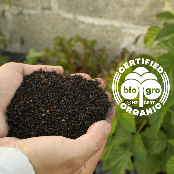 Hand holding organic soil with BioGro certification logo in the corner