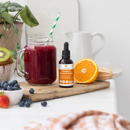 A bottle of Children's Immune Drops with fruits and a berry smoothie.